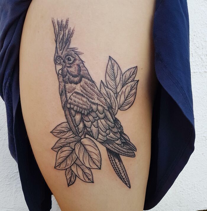 Tattoo of a cockatiel perched on leaves celebrating pet beauty.