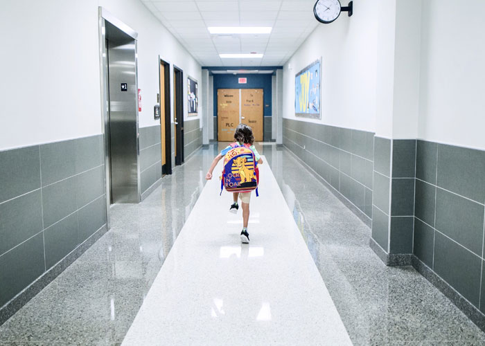 Child running down a bright, empty hallway in a workplace building, evoking disturbing things seen at work experiences.