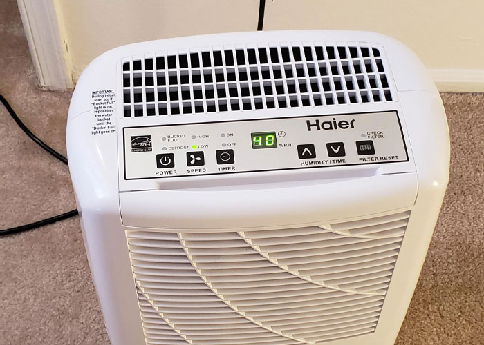 Dehumidifier operating in a carpeted room, showing humidity control panel and air vents for homeowning tips.