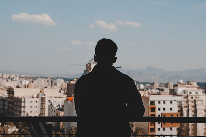 man standing on the balcony with the city view 