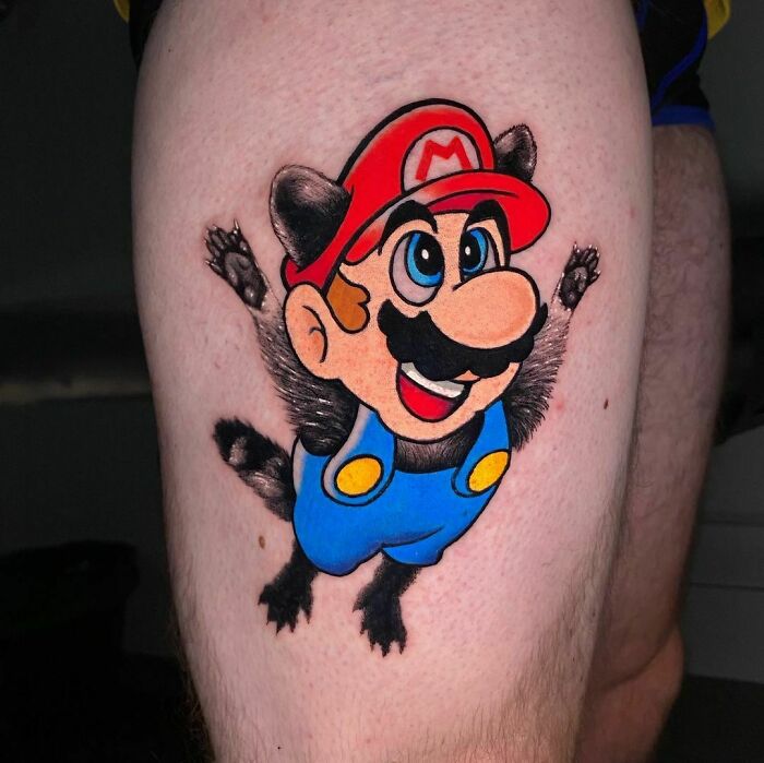 Cartoon tattoo of a classic video game character with raccoon suit, colorful and nostalgic on a person's leg.