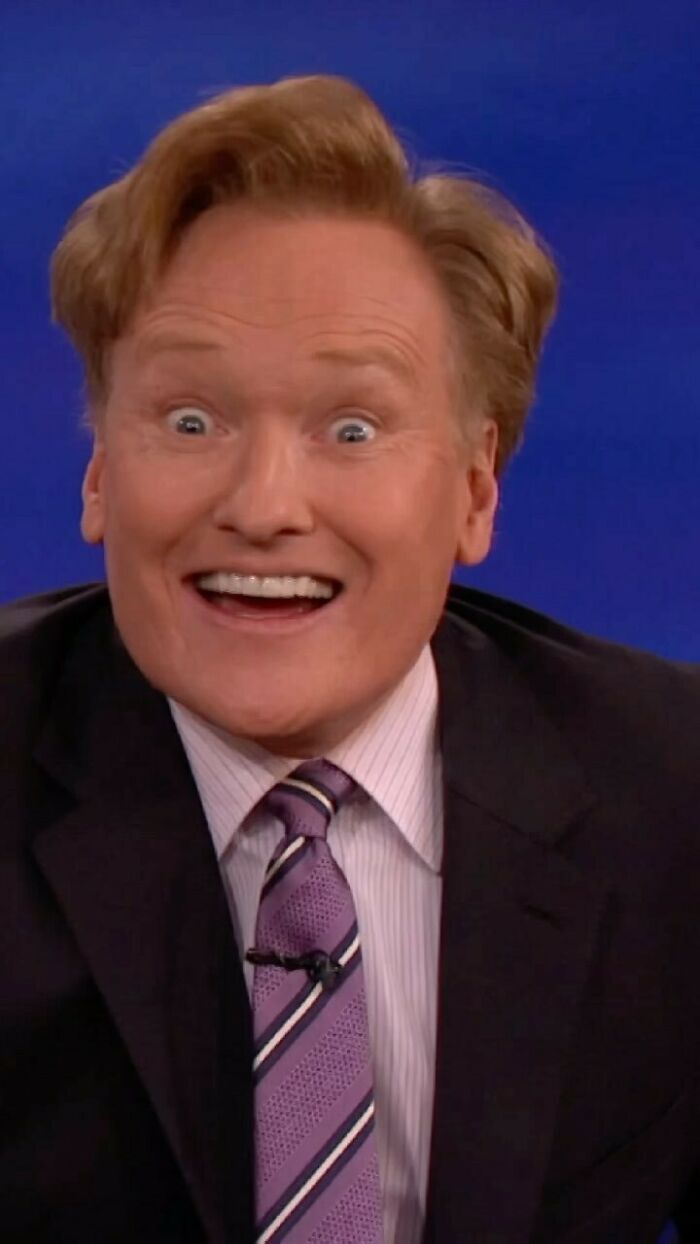 Comedian on a talk show set, smiling widely, representing smartest celebrities known for talent and intelligence.