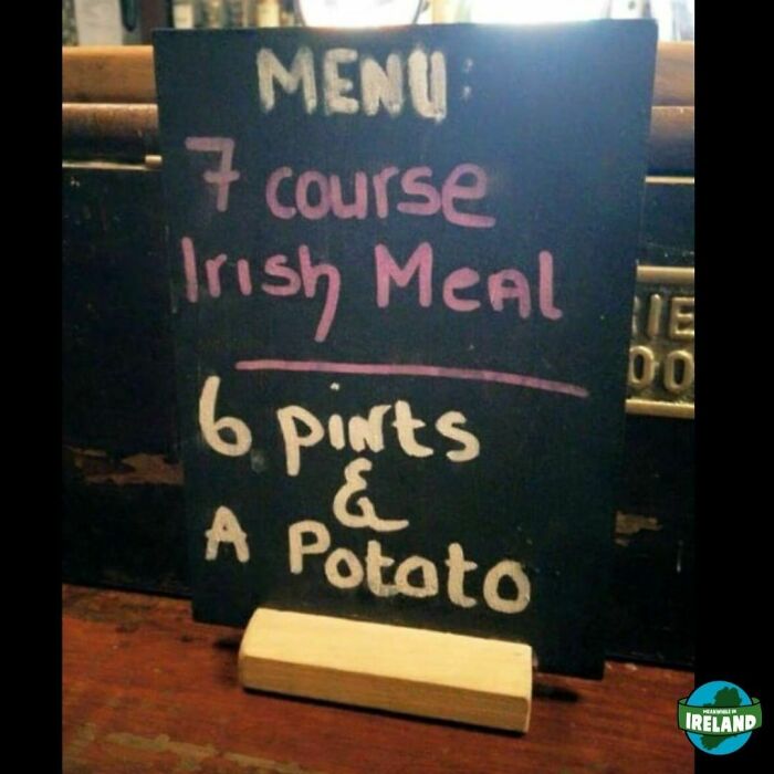 Chalkboard menu in Ireland advertising a 7-course Irish meal with 6 pints and a potato in a rustic setting