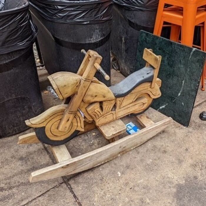 Wooden rocking motorcycle found discarded on the street, showcasing the idea of one man's trash being another man's treasure.