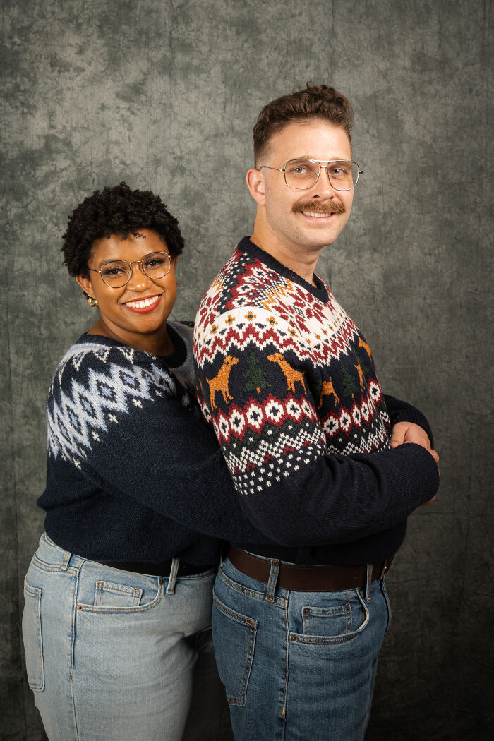 Couple posing in 80s-themed sweaters, smiling together for an anniversary photoshoot.