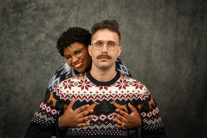 Couple in an awkward 80's photoshoot with patterned sweaters and glasses, celebrating anniversary.
