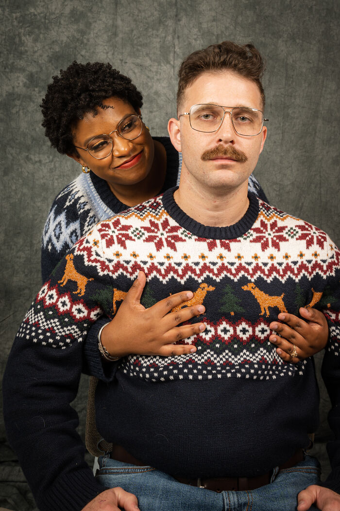 Couple in an awkward 80's photoshoot, wearing vintage sweaters against a gray backdrop.