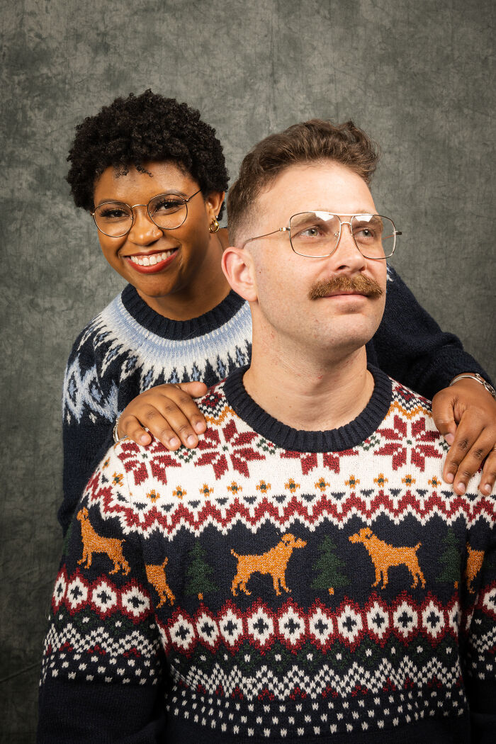 Couple posing in 80's style sweaters with glasses for an awkward anniversary photoshoot.