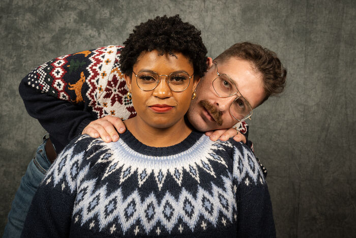 Couple in 80's-style sweaters striking a pose for an anniversary photoshoot.