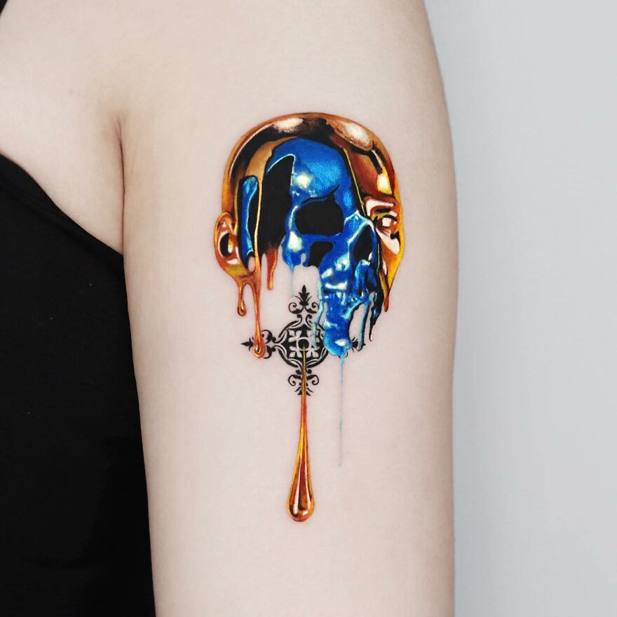 Golden and blue skull tattoo on arm, designed by a Manhattan-based tattoo artist.