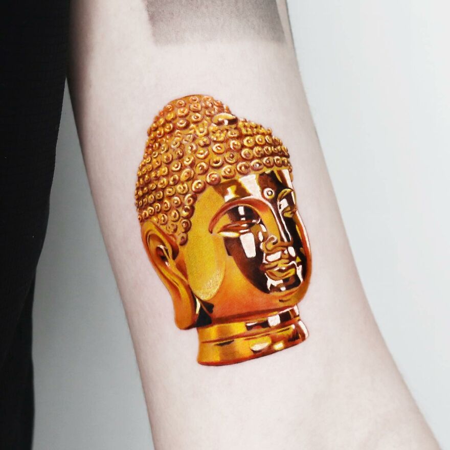 Golden Buddha tattoo on arm, designed by Manhattan-based artist, showcasing precision and detail.