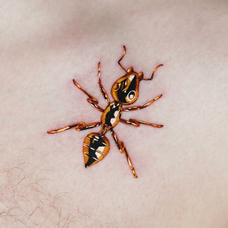 Golden ant tattoo on skin, designed with precision by Manhattan-based artist.