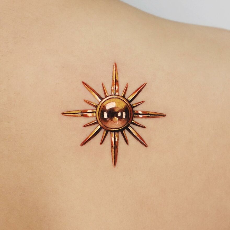Golden tattoo of a radiant sun design on skin by Manhattan-based artist.