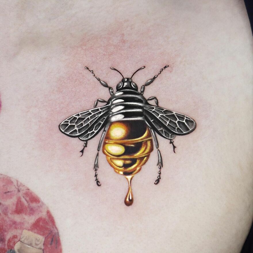 Golden tattoo of a bee with intricate details by Manhattan-based artist.