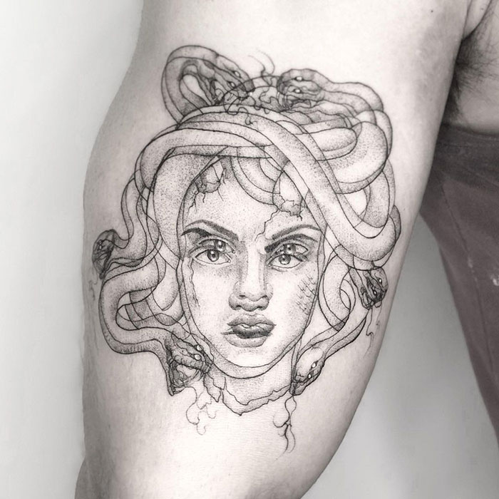 Trippy Medusa tattoo with swirling snakes on blurred arm, showcasing detailed line art.