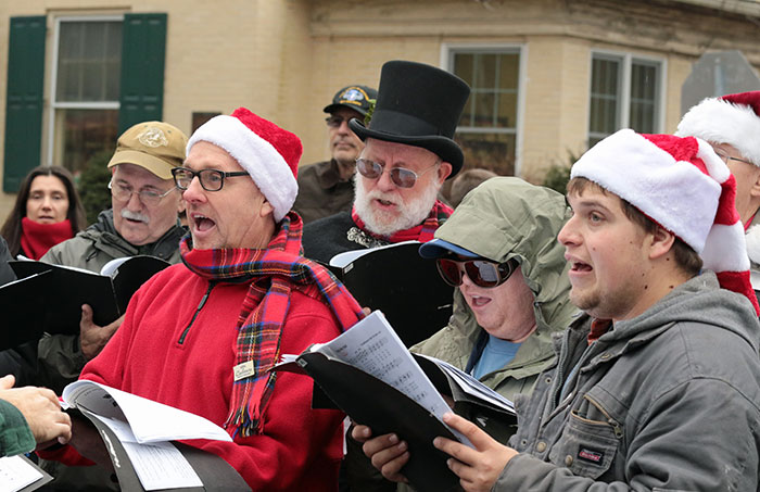 Persons standing wearing Christmas hats and singing