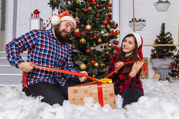 Picture of family opens gift near Christmas tree