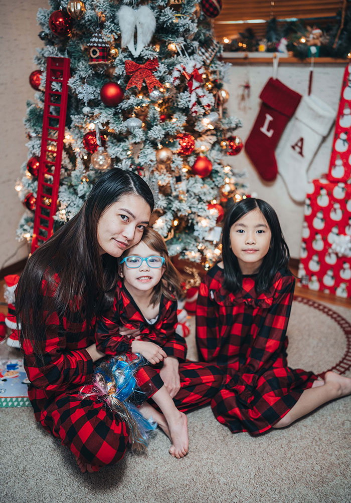 Family wearing Christmas pajamas and sitting near Christmas tree