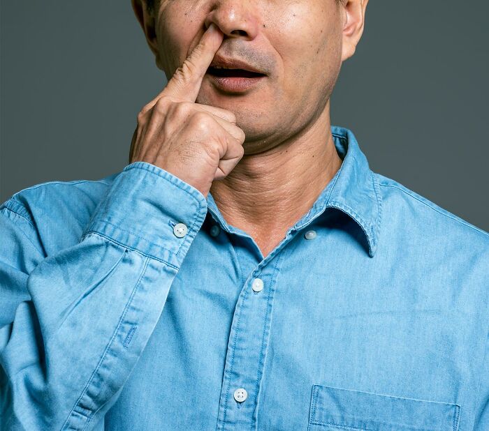Man in a blue shirt picking his nose, illustrating one of the things basically everyone does but pretend not to.