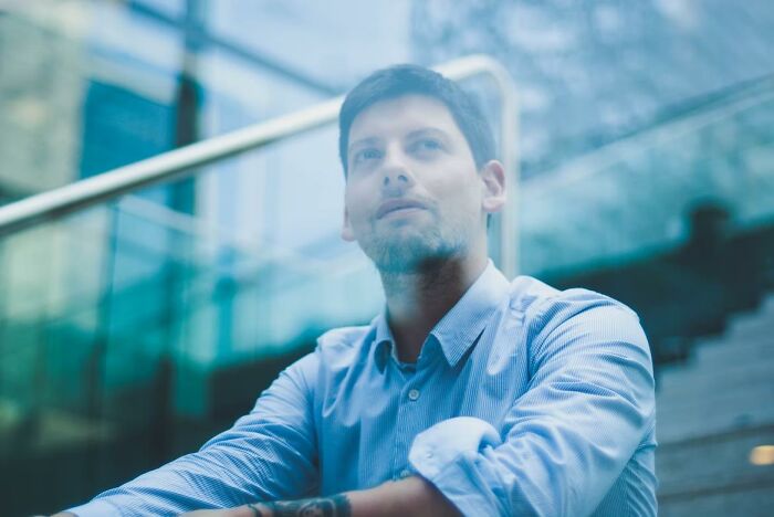 Man wearing a blue shirt looking thoughtful, illustrating common habits nobody wants to admit doing.