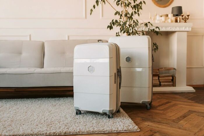 Two white suitcases on wheels placed on a rug in a living room, illustrating criminally overpriced items discussion.