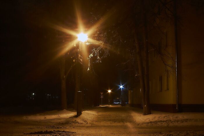 Dimly lit snowy street at night with warm streetlights, evoking a nostalgic Gen X memory lane atmosphere.