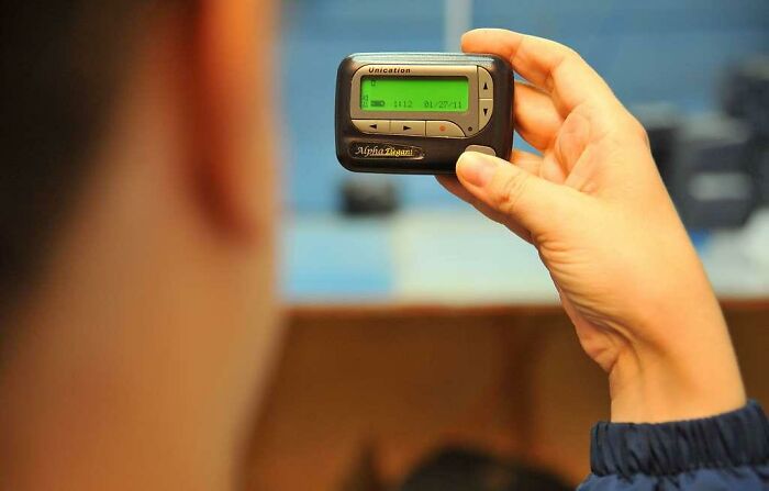 Person holding a classic pager, symbolizing nostalgic Gen X technology and memories from the past.