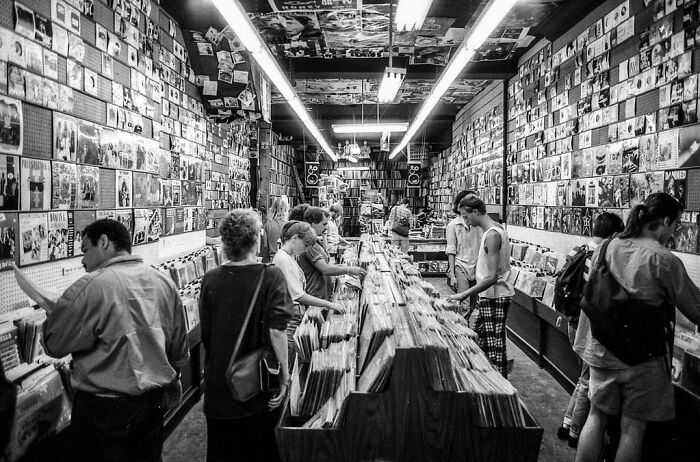 Black and white photo of people browsing vinyl records in a store, evoking nostalgic Gen X memories.