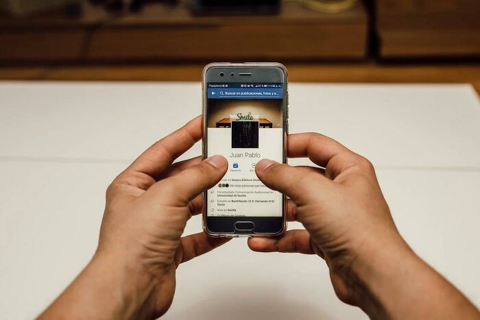 Person holding smartphone showing a social media profile, illustrating life-saving tips shared by a private investigator.