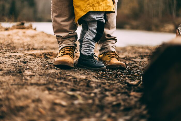 Adult and child wearing boots standing close together on a dirt path, illustrating fear of going downstairs after turning off the lights.
