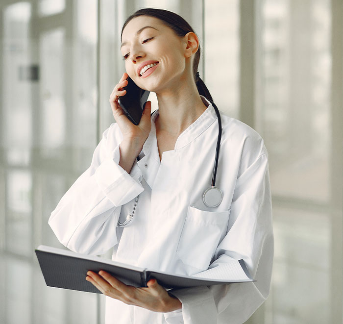 Female doctor with stethoscope talking on phone while reviewing patient notes, illustrating second opinion stories.