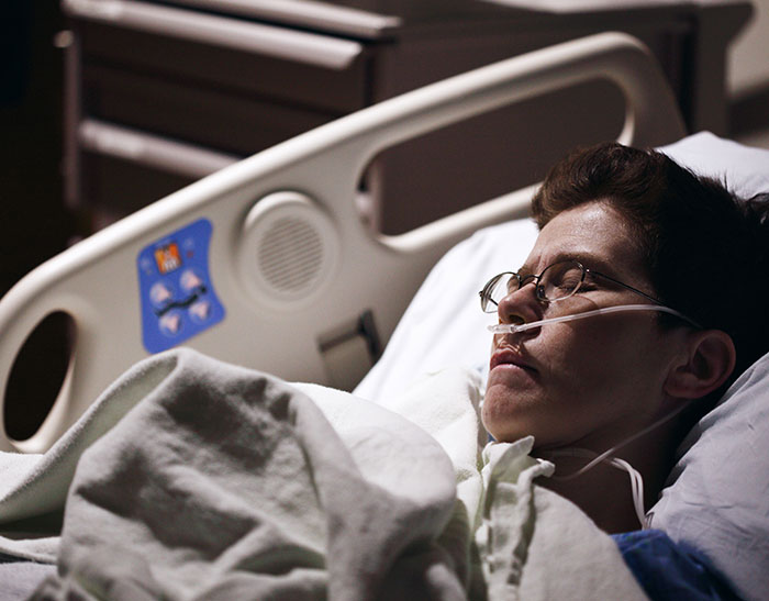 Patient in hospital bed with oxygen tube resting quietly, illustrating doctors sharing second opinion stories.