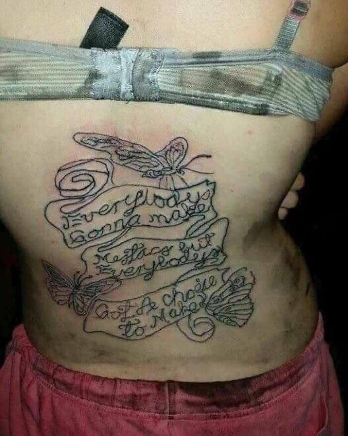 Bad tattoo with misspelled script and butterflies on someone's torso.