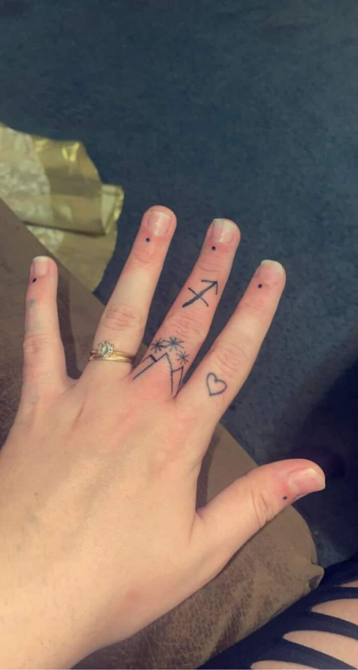 Unusual finger tattoos featuring dots, an arrow, mountains with stars, and a heart, illustrating hilariously bad ink choices.