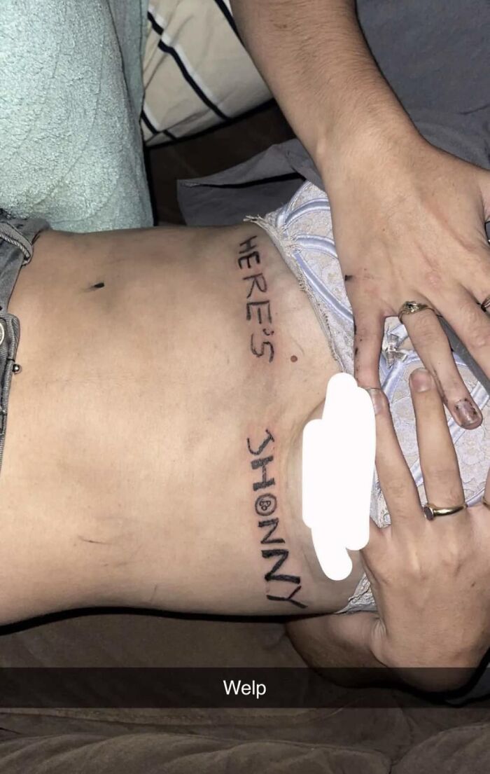 Bad tattoo on a person’s side with misspelled text alongside their hand and shorts, showcasing tattoo inkshaming.