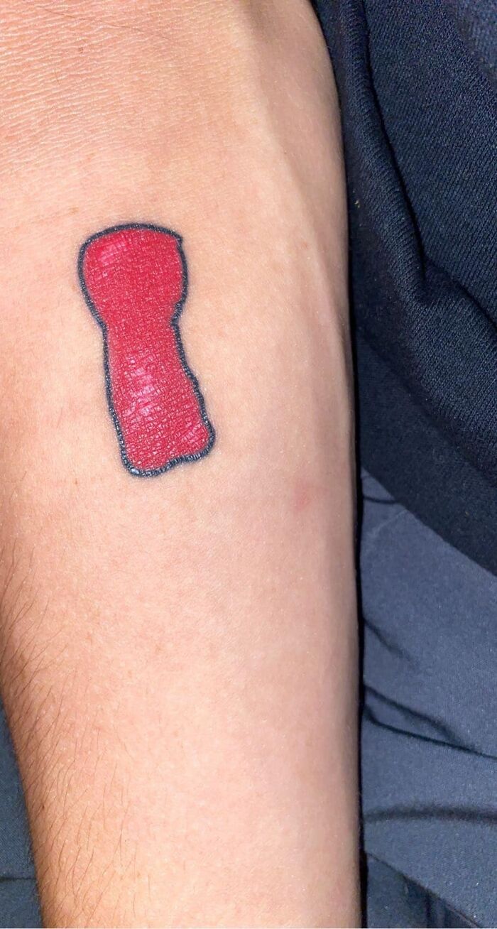 Poorly drawn red tattoo on skin, resembling a bottle, highlighting bad tattoos.