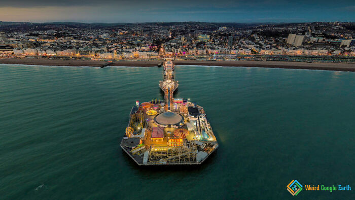 Aerial view of a lit-up amusement pier extending into the ocean, showcasing amusing and ridiculous moments on Google Maps.