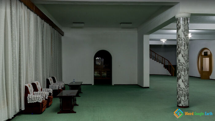 Empty room with vintage chairs and tables, a marble column, and staircase in an amusing Google Maps moment.
