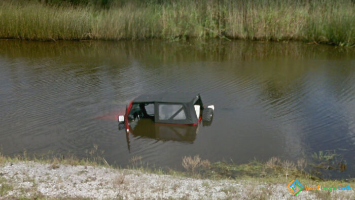Partially submerged car in a pond, one of the most amusing and ridiculous moments captured by Google Maps.