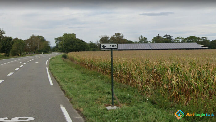 Road sign with the word sus pointing left near a cornfield, one of the amusing moments captured by Google Maps.