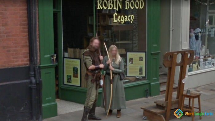 Two people dressed in medieval Robin Hood costumes captured in an amusing Google Maps moment on a street corner.
