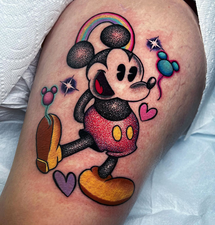 Colorful glitter tattoo of a cartoon character with rainbow, stars, and hearts on skin. Unique and cool design.