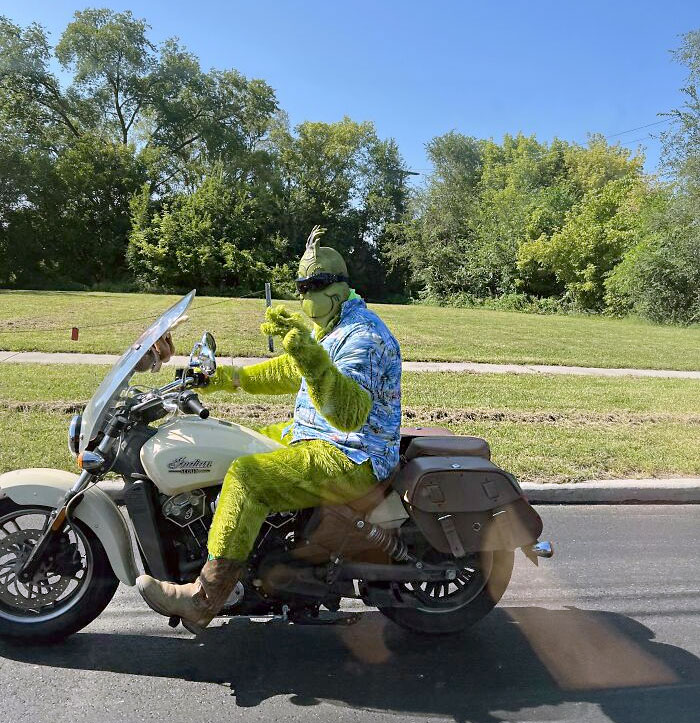 Person in a Grinch costume on a motorcycle, bringing humor to Christmas on the road.