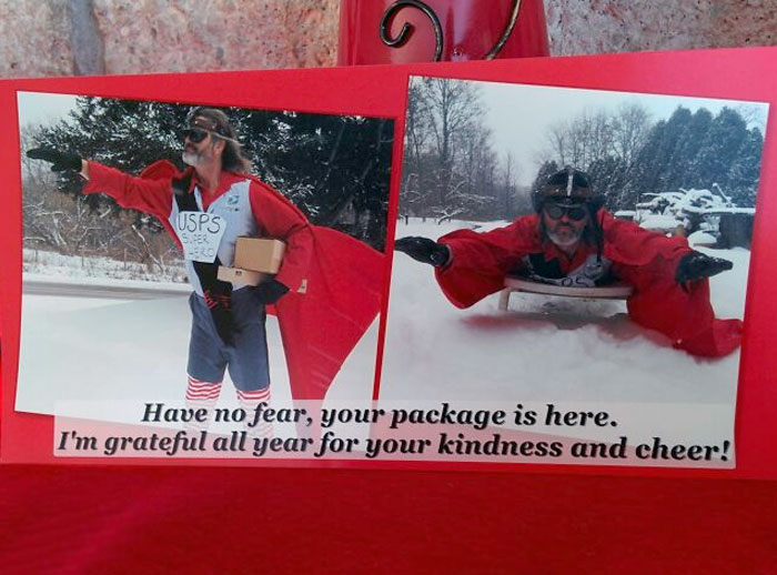 Person dressed as USPS superhero delivering packages, adding humor to Christmas celebrations.