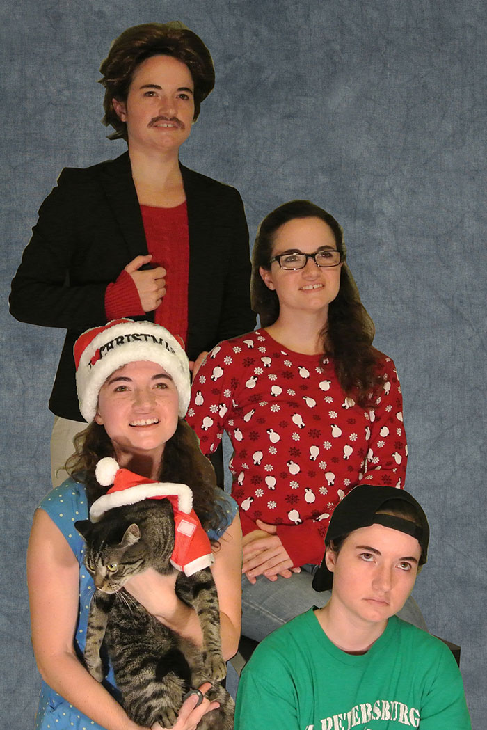 Group of people in holiday outfits, one with a Santa hat holding a cat, showcasing humor during Christmas.