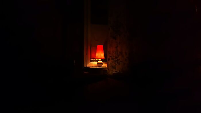 Dimly lit room with a red lamp glowing softly, illustrating the fear of going downstairs after turning off the lights alone.