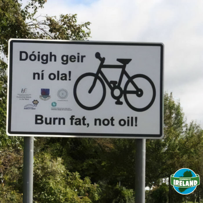 Road sign in Ireland encouraging cycling with the message burn fat, not oil, highlighting unique Ireland culture.