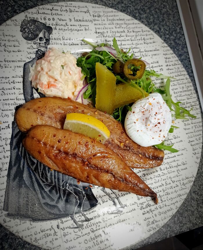 Plate with grilled fish, lemon wedge, coleslaw, greens, pickles, and a poached egg from a dish rating Facebook group.