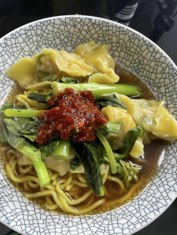 Bowl of noodles with dumplings, greens, and chili sauce, featured in a Facebook group where people rate dishes.
