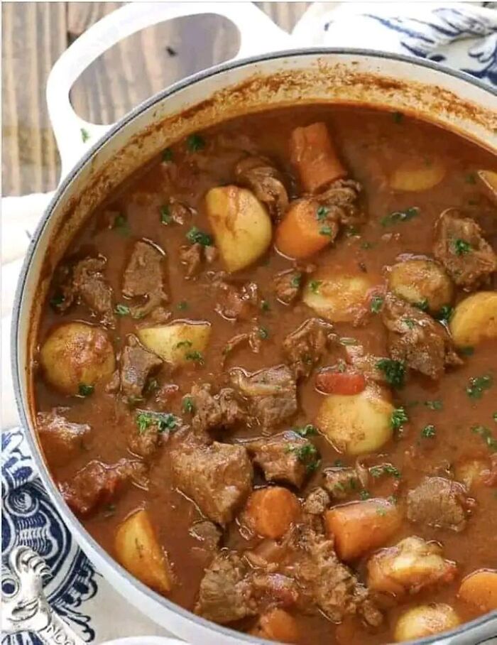 Hearty beef stew with potatoes and carrots served in a white pot, featured in a dish rating Facebook group.